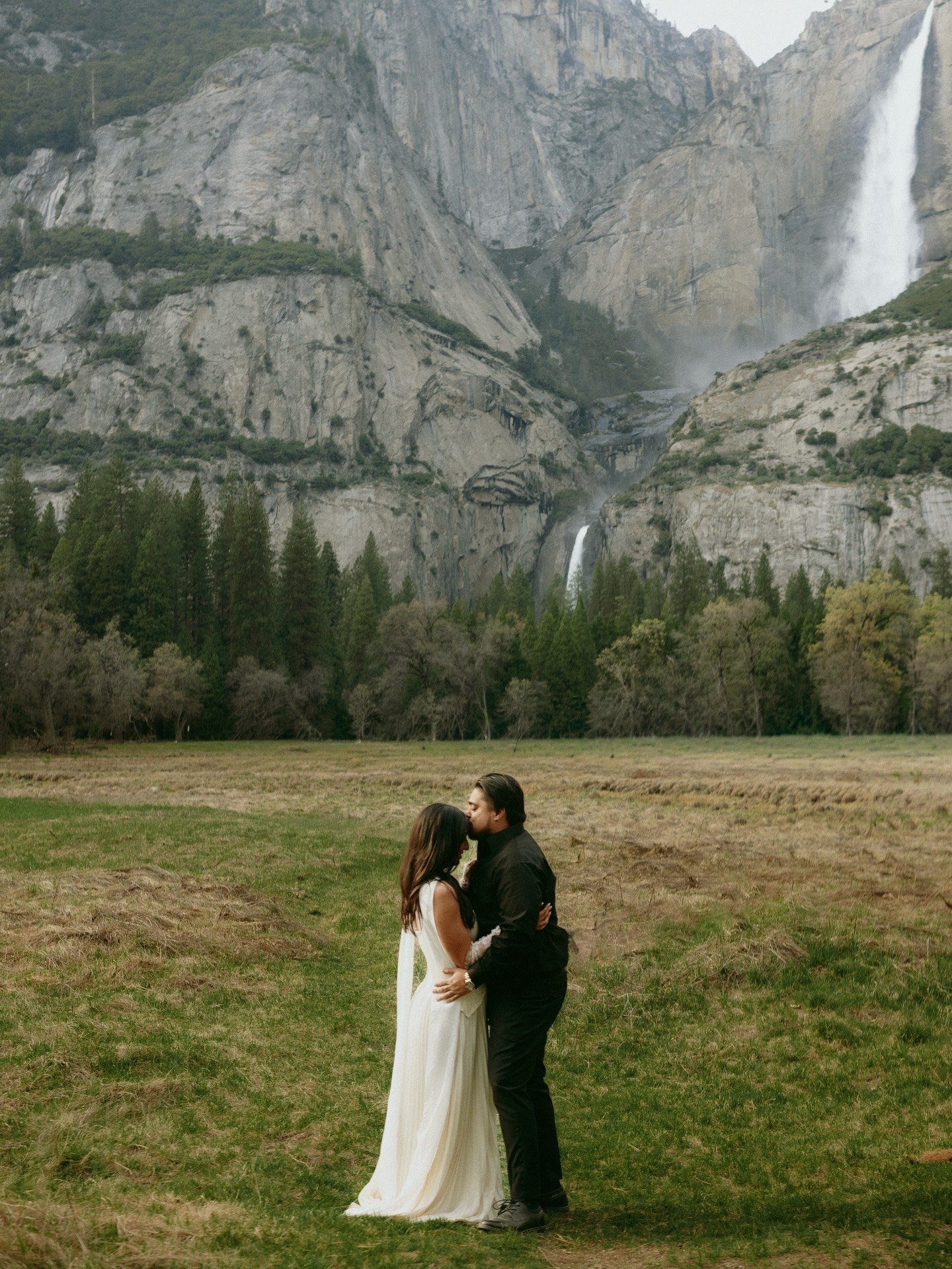 Tamara and Christian sharing a kiss in front of Yosemite Falls