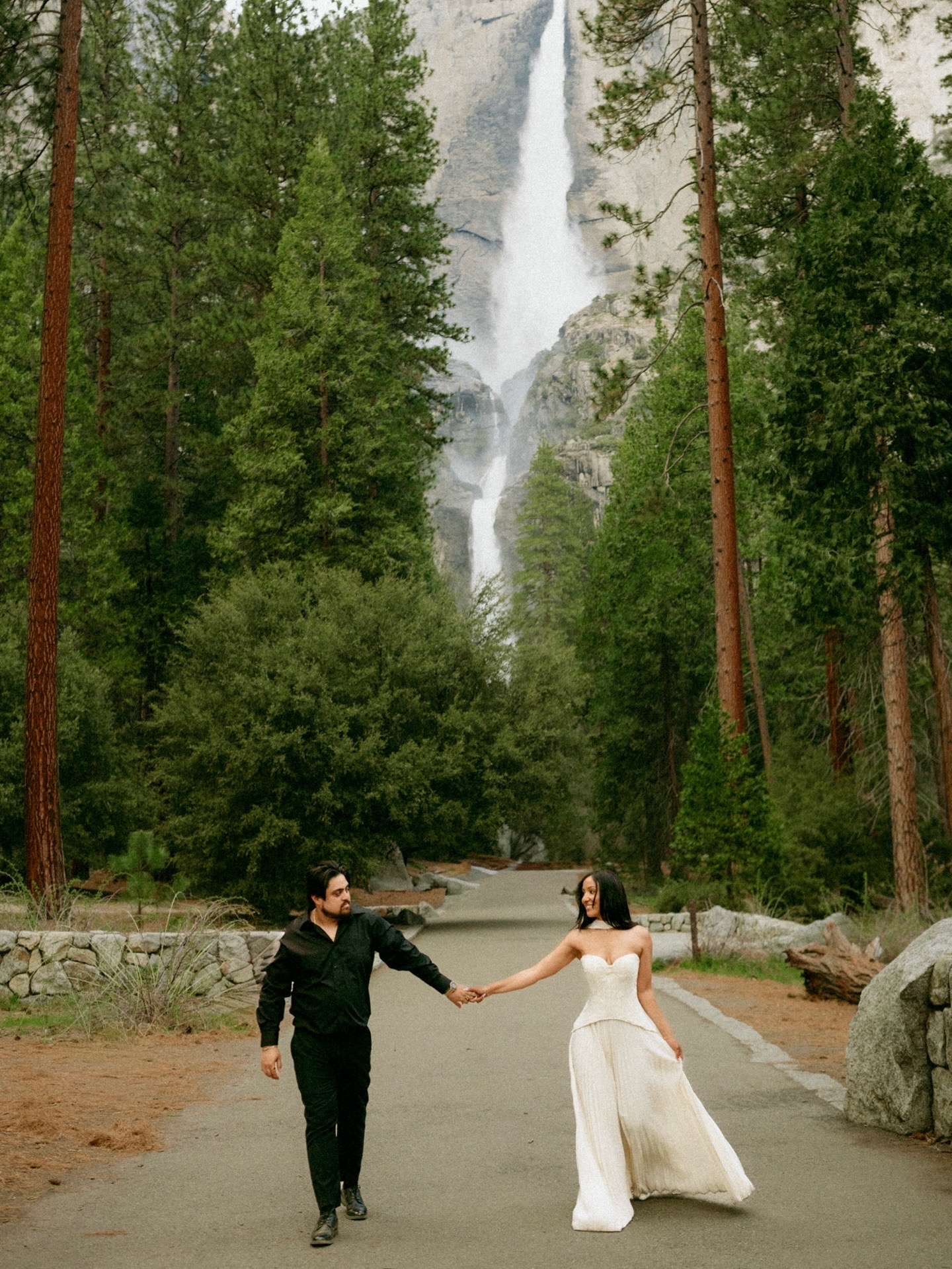 Tamara and Christian holding hands in front of Yosemite Falls