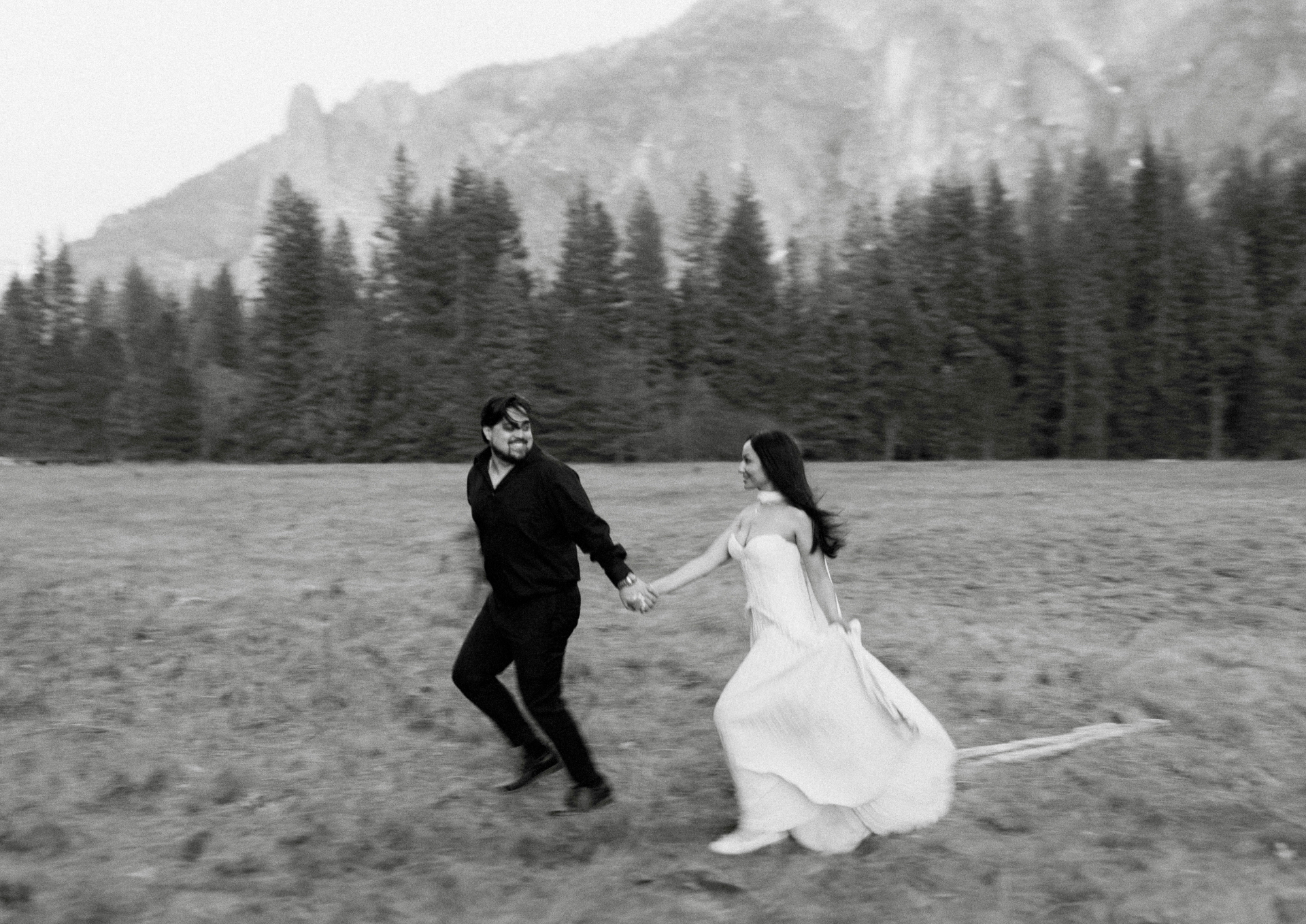 Black and white photo of Tamara and Christian running together in a meadow